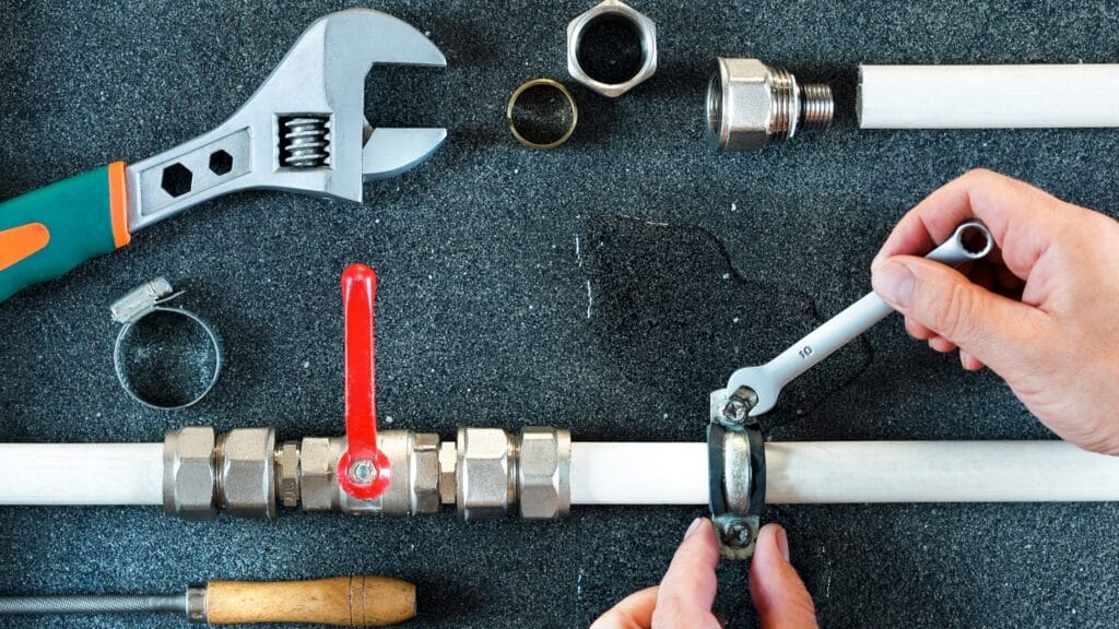 Plumber repairing a pipe valve with an adjustable wrench in San Ramon