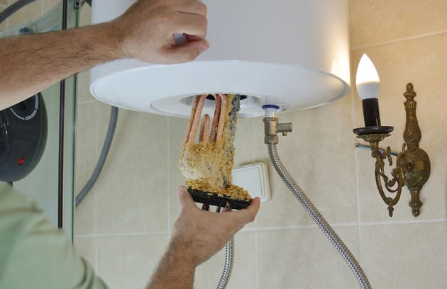 Technician removing mineral buildup from a water heater in San Ramon