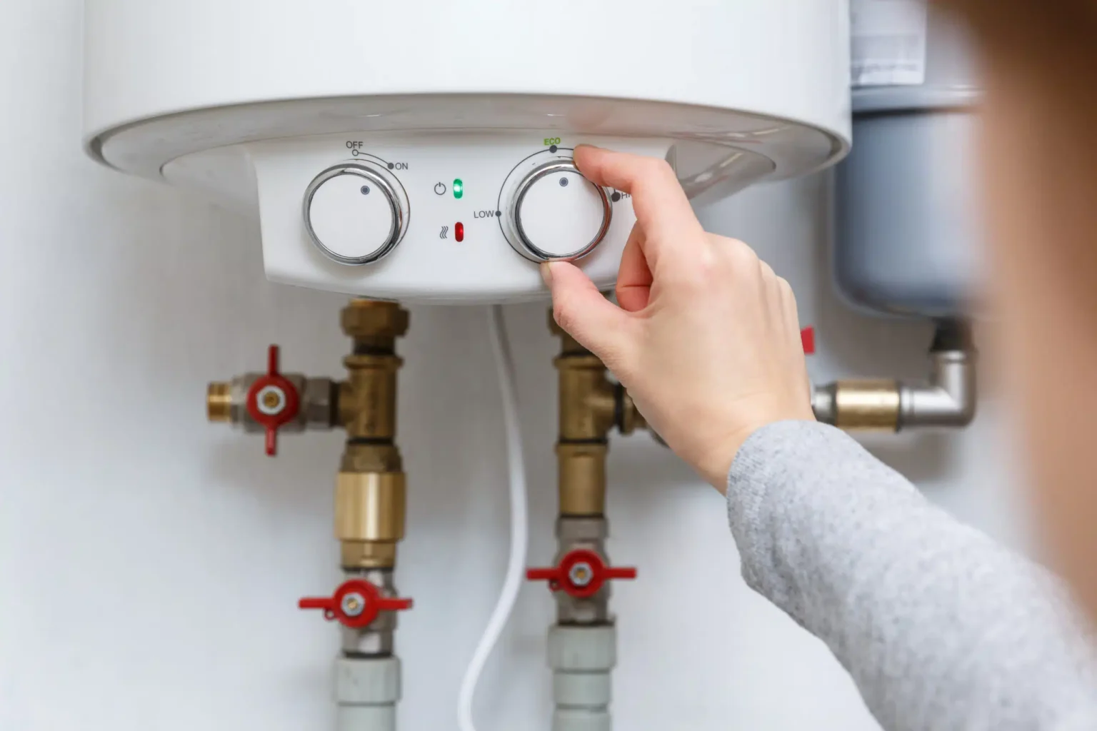 Homeowner adjusting the temperature controls on a water heater in San Ramon